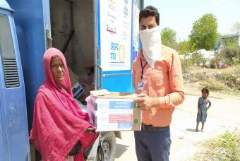 Volunteer hands out a relief kit to a woman 